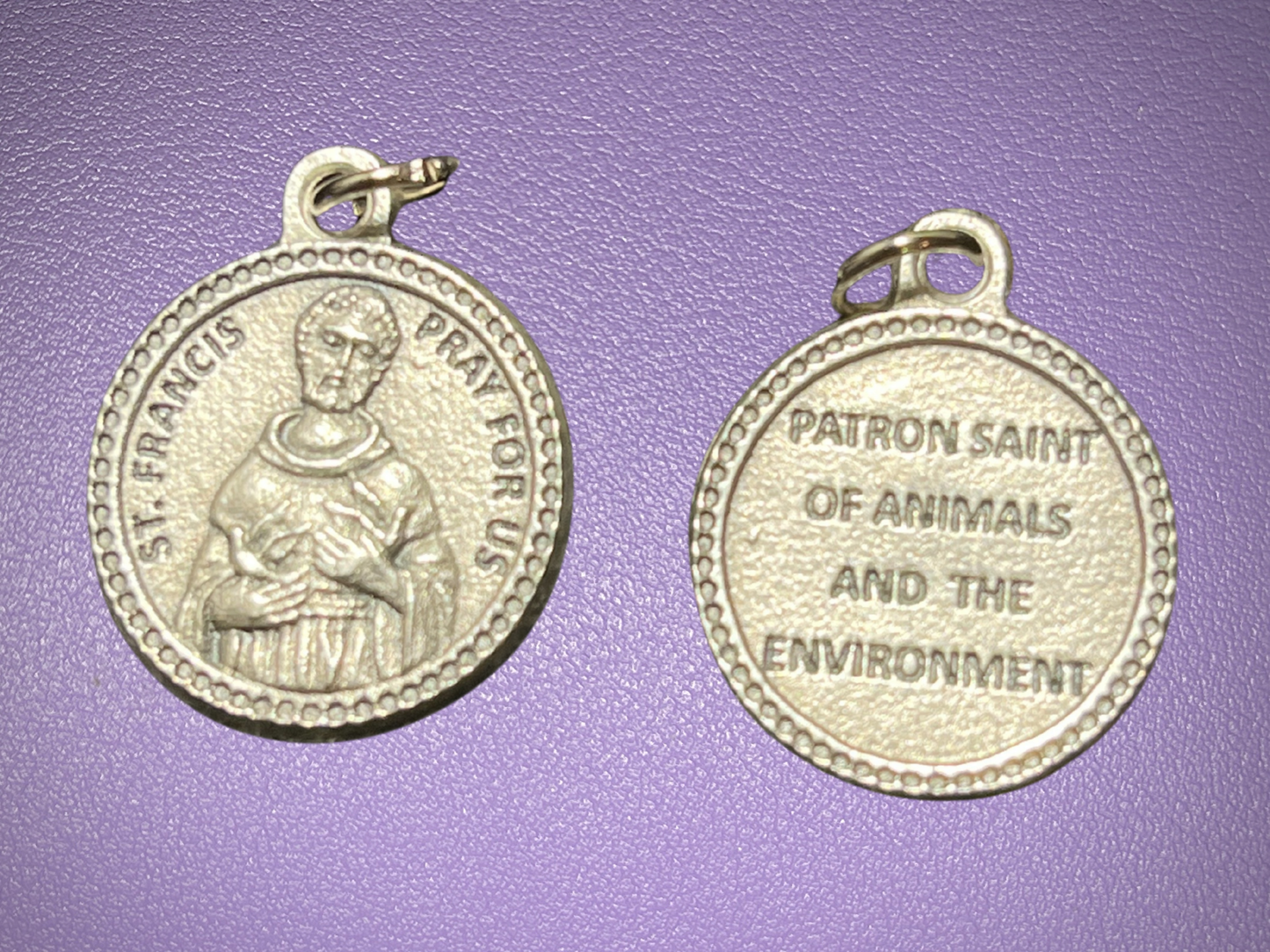 Two silver medals with engravings on a purple background