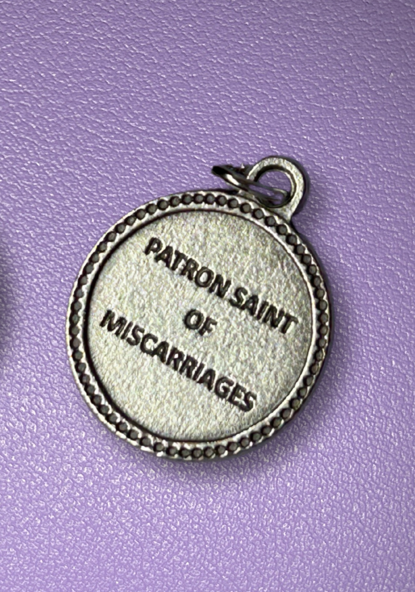 Silver religious pendant on a purple background