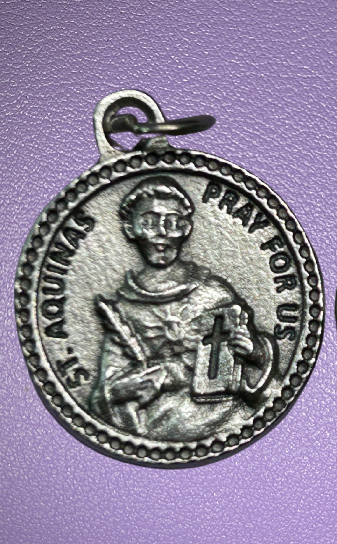 Silver medal with St Thomas Aquinas figure and text on a purple background